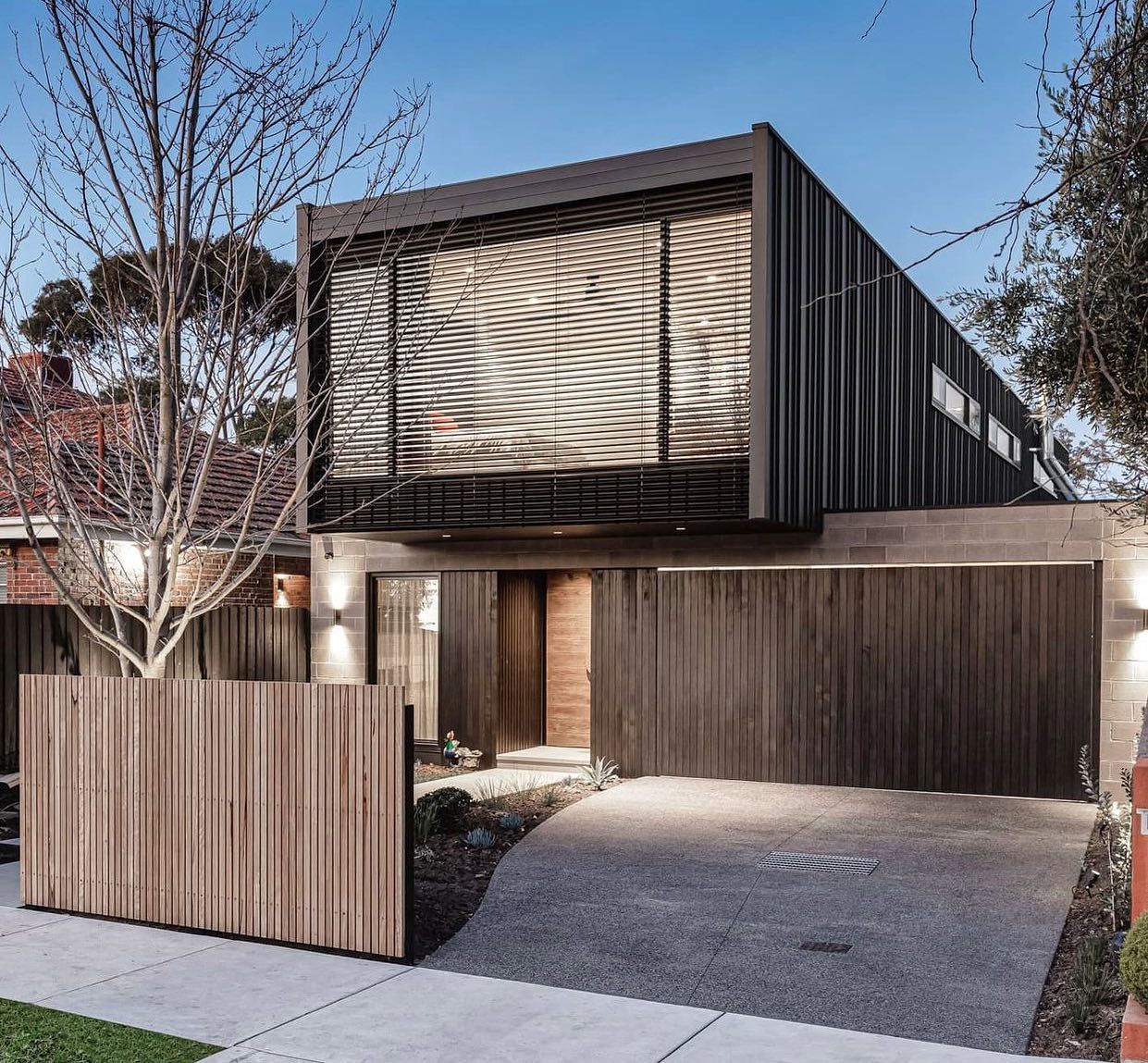 A modern home with a concrete driveway and wooden fence.