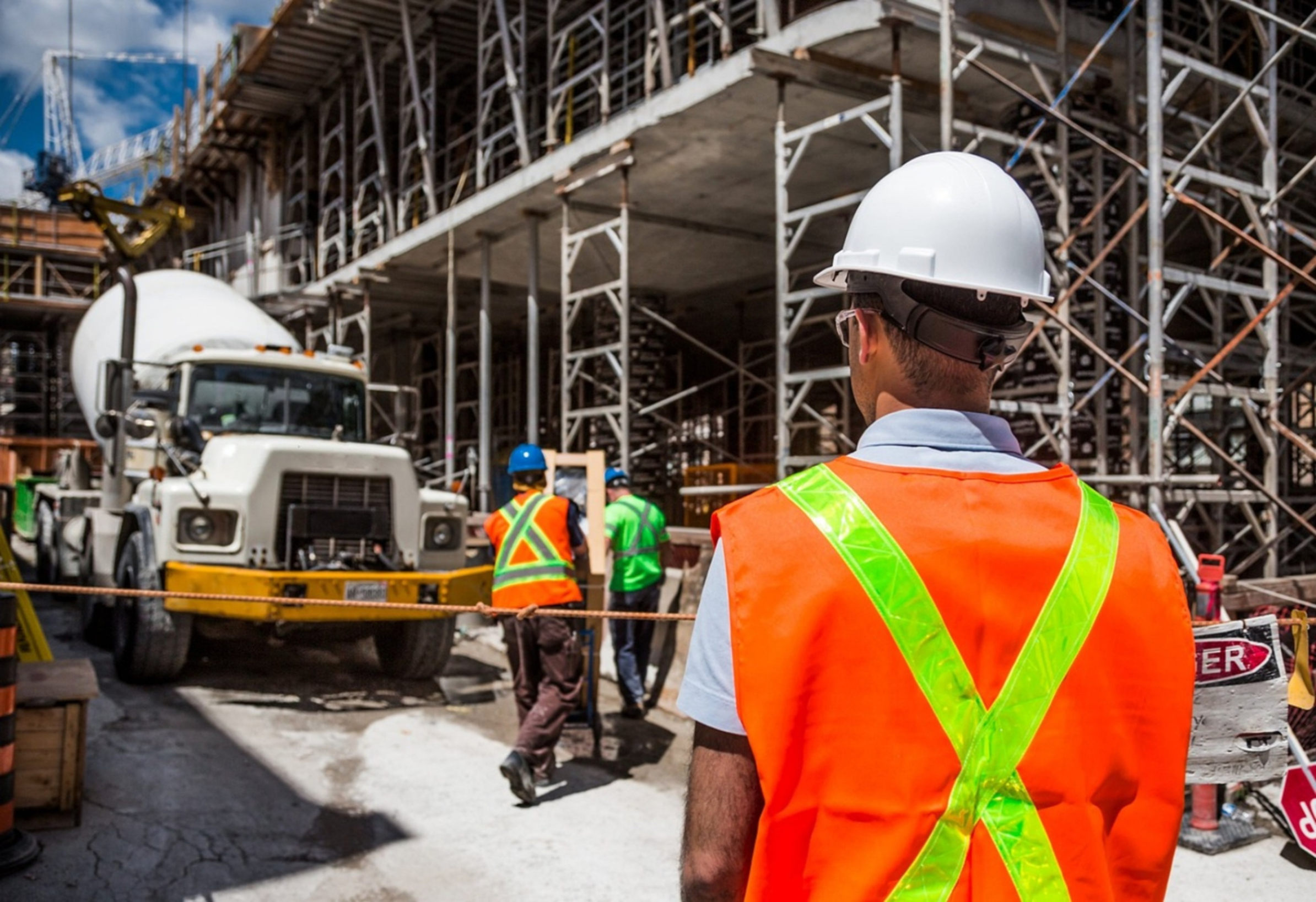 A man wearing construction PPE is observing the construction work.